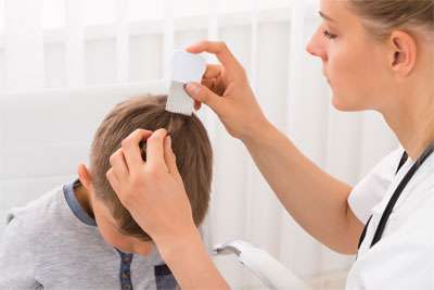 Child with head lice being treated by a nurse