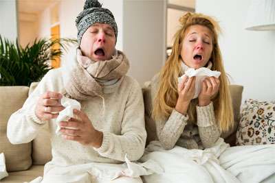Husband and wife with common cold sneezing