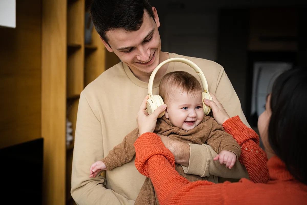 woman and man holding child wearing protective headphones